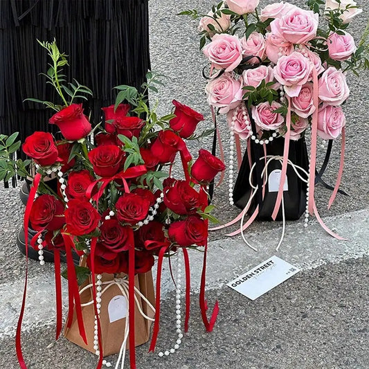 The image shows two foldable waterproof flower bags, one black and one pink, displayed alongside a arrangement of red and pink roses.