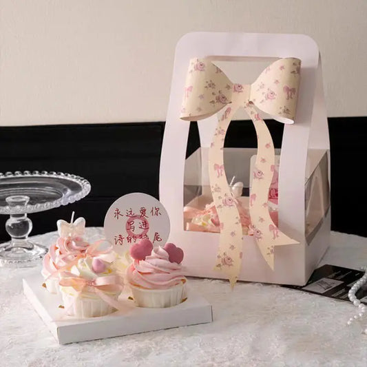 Cupcake gift box with clear window and large floral bow, elegant bakery packaging.