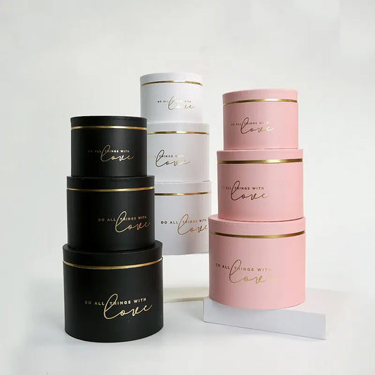 Gold rim round flower gift boxes in black, white, and pink with elegant design.