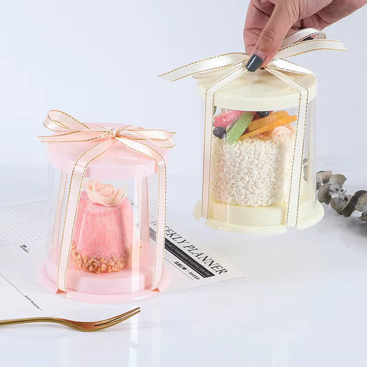 Set of round clear cake boxes with ribbons in assorted colors.