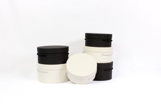 A collection of round cardboard boxes with handles, available in black and white colors.