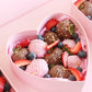 Pink heart box zoomed in. Showcasing chocolate covered strawberries. 