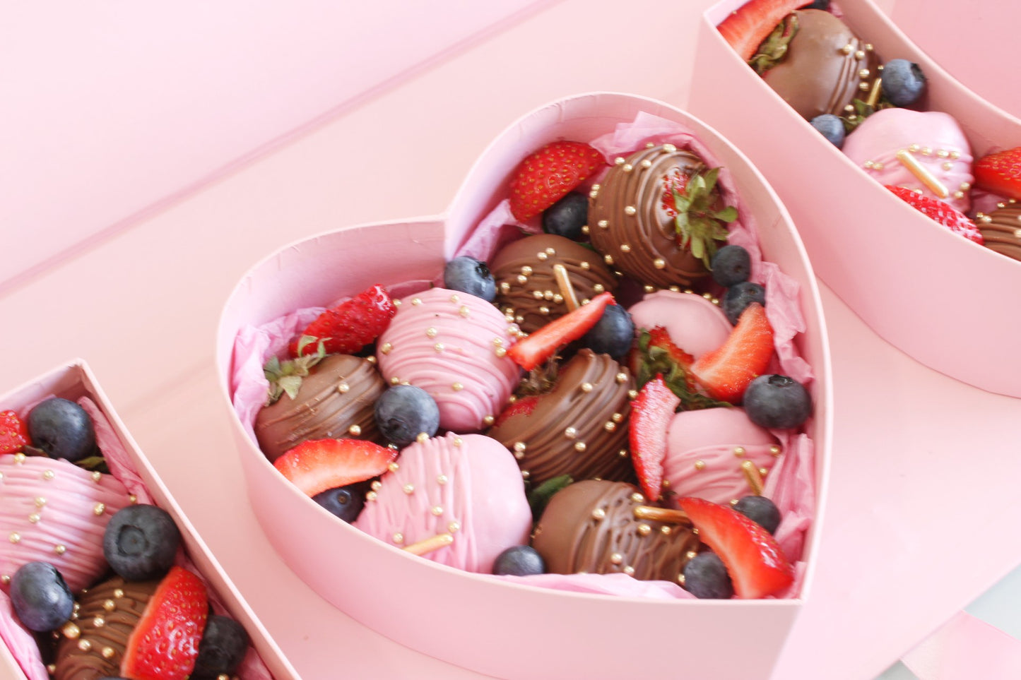 Pink heart box zoomed in. Showcasing chocolate covered strawberries. 